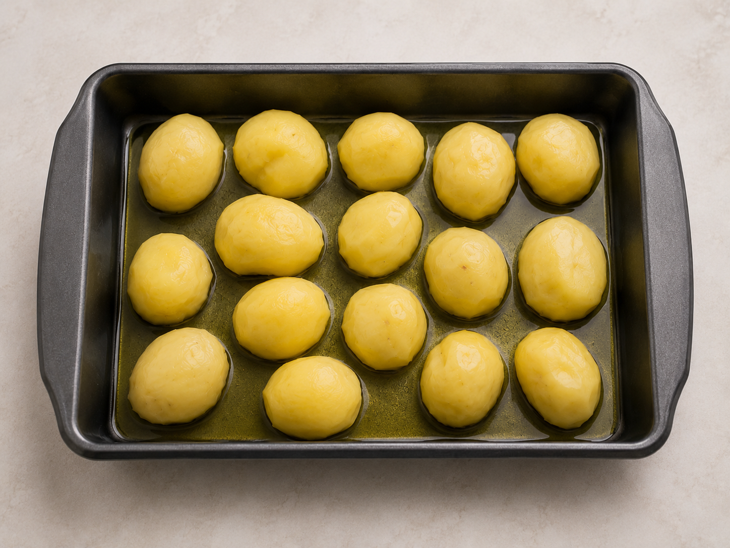 Parboiled potatoes arranged in a roasting pan